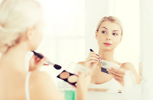 Frau mit Schminkpinsel und Fundament im Badezimmer — Stockfoto