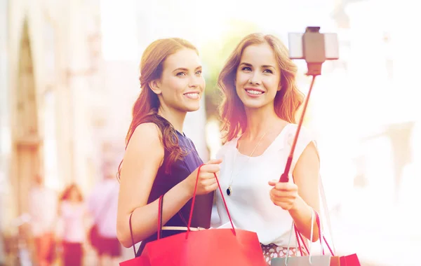 Vrolijke vrouwen met boodschappentassen en smartphone — Stockfoto