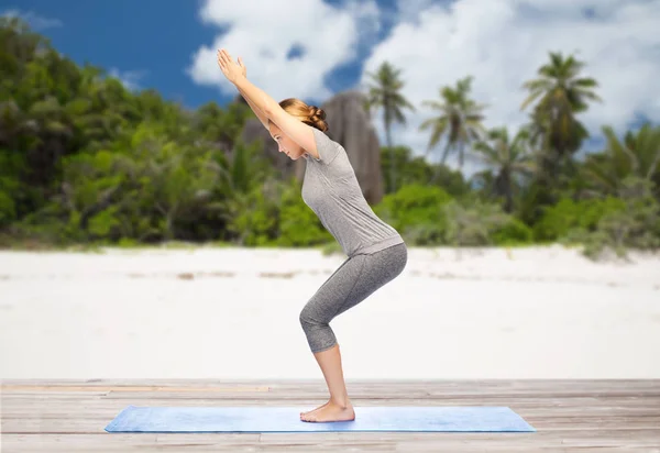 Vrouw doet yoga stoel pose op strand — Stockfoto