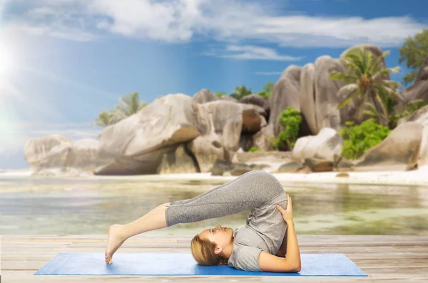 Frau macht Yoga in Pflugpose am Strand — Stockfoto