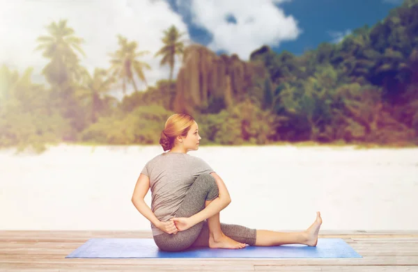 Kvinnan gör yoga i twist pose på stranden — Stockfoto