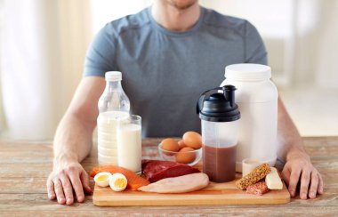 close up of man with food rich in protein on table clipart
