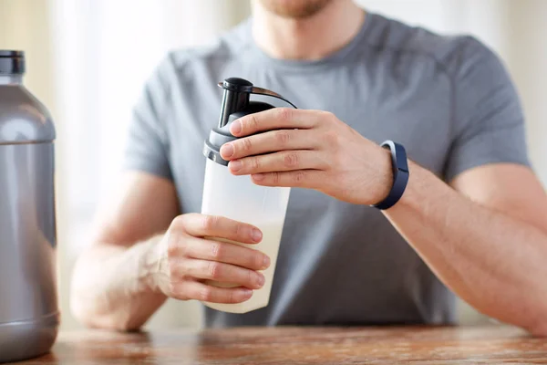 Primo piano dell'uomo con bottiglia e barattolo di frullato proteico — Foto Stock