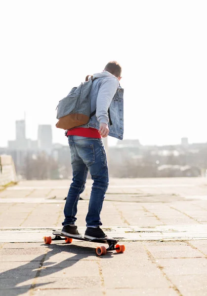 Jovem feliz ou adolescente montando em longboard Fotografia De Stock