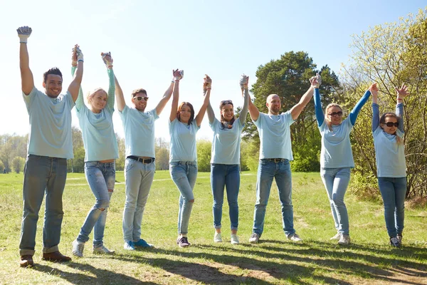 Skupina happy dobrovolníků, drželi se za ruce venku — Stock fotografie