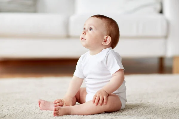 Щасливий маленький хлопчик або дівчинка сидить на підлозі вдома — стокове фото