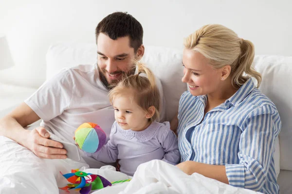 Família feliz com smartphone na cama em casa — Fotografia de Stock