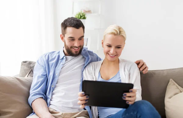 Sorridente coppia felice con tablet pc a casa — Foto Stock