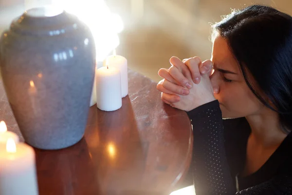 Mujer triste con urna funeraria rezando en la iglesia — Foto de Stock