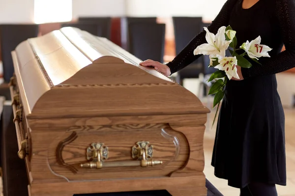 Woman with lily flowers and coffin at funeral — Stock Photo, Image