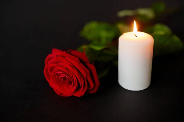 Red rose and burning candle over black background — Stock Photo, Image