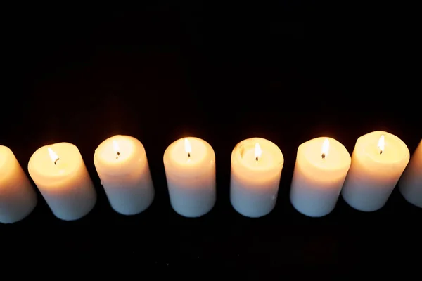 Candele che bruciano nel buio su sfondo nero — Foto Stock