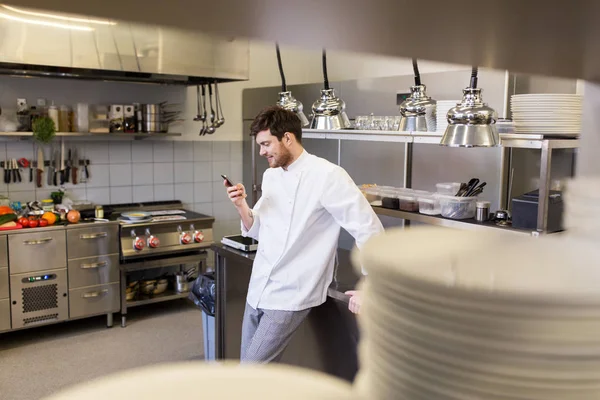 Koch kocht mit Smartphone in Restaurantküche — Stockfoto