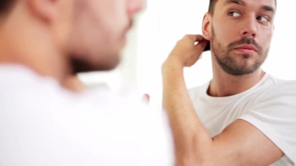 Happy man brushing hair with comb at bathroom — Stock Video