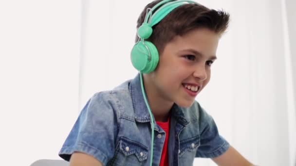 Niño en auriculares jugando videojuego en el ordenador portátil — Vídeos de Stock