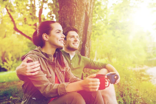 Happy couple with cups drinking in nature — Stock Photo, Image