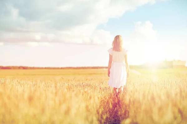 Mujer joven en vestido blanco caminando por el campo — Foto de Stock