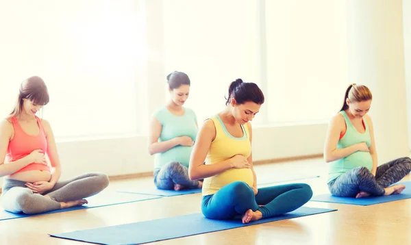 Mujeres embarazadas felices ejercitando yoga en el gimnasio —  Fotos de Stock