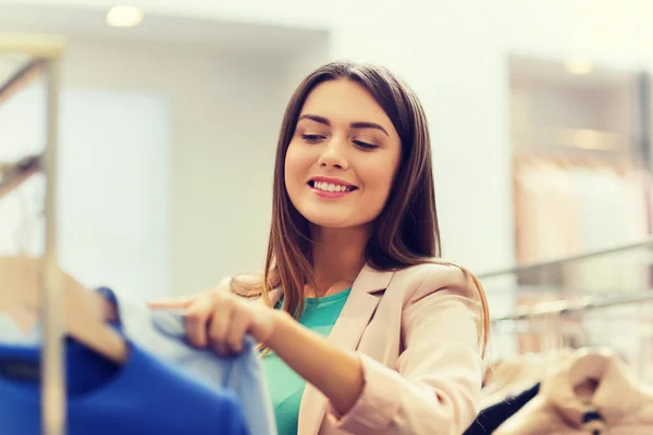 Feliz joven mujer elegir ropa en el centro comercial — Foto de Stock