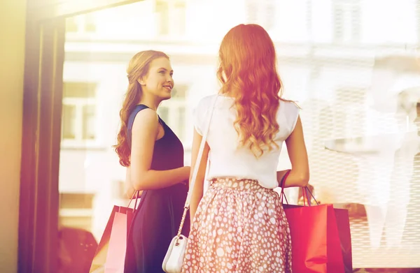 Mujeres felices con bolsas de compras en el escaparate — Foto de Stock