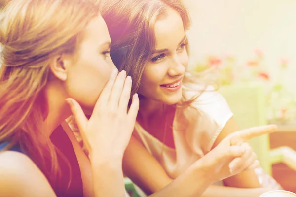 Smiling young women gossiping at outdoor cafe — Stock Photo, Image