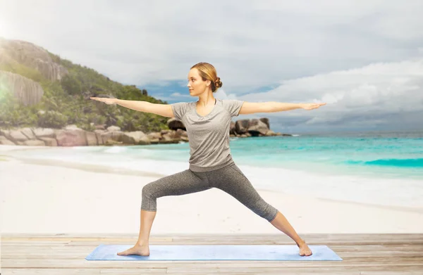 Vrouw doet yoga warrior pose op strand — Stockfoto