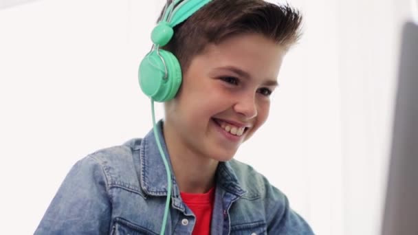 Хлопчик в навушниках грає у відеогру на ноутбуці — стокове відео