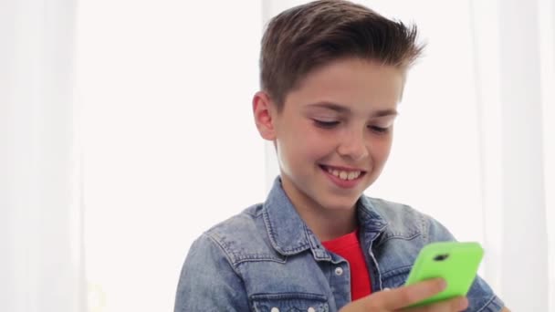Niño sonriente feliz con teléfono inteligente en casa — Vídeo de stock