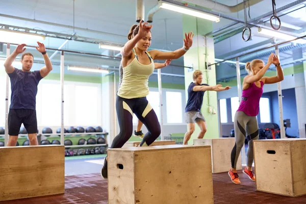 Groupe de personnes faisant des sauts de boîte exercice dans la salle de gym — Photo