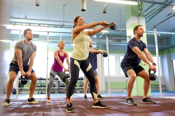 Group of people with kettlebells exercising in gym — Stock Photo, Image