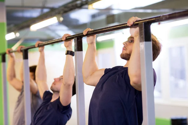 Skupina mladých mužů dělá pull-up v tělocvičně — Stock fotografie