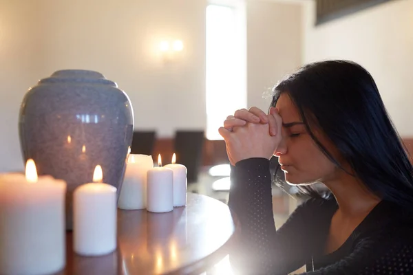 Treurige vrouw met funeraire urn bidden in kerk — Stockfoto