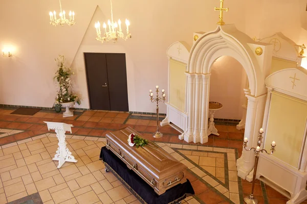 Kista med blommor och stå på begravning i kyrka — Stockfoto