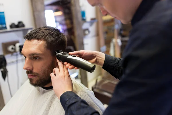 Uomo e barbiere con trimmer taglio capelli al salone — Foto Stock