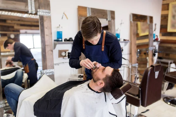 Homem e barbeiro com barba de corte aparador no salão — Fotografia de Stock