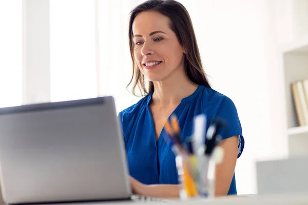 Счастливая женщина с ноутбуком, работающая дома или в офисе — стоковое фото