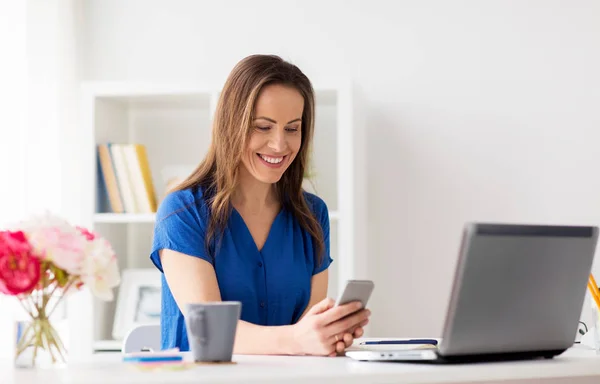 Mujer con teléfono inteligente y portátil en la oficina — Foto de Stock