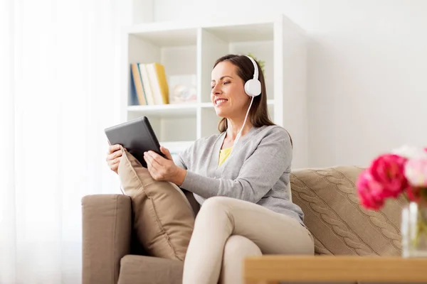 Lycklig kvinna med TabletPC och hörlurar hemma — Stockfoto