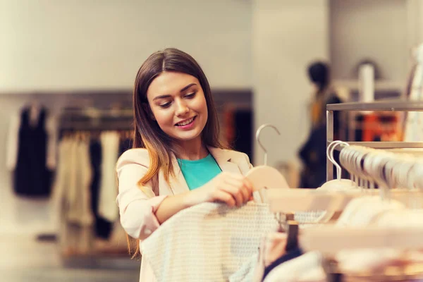 Glückliche junge Frau wählt Kleidung in Einkaufszentrum — Stockfoto