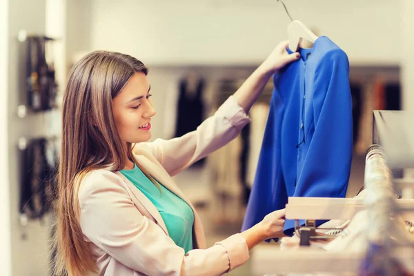 Feliz joven mujer elegir ropa en el centro comercial — Foto de Stock