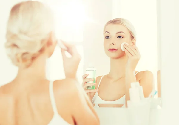 Молода жінка з лосьйоном миття обличчя у ванній — стокове фото