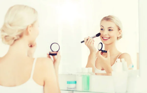 Mulher com escova de maquiagem e blush no banheiro — Fotografia de Stock