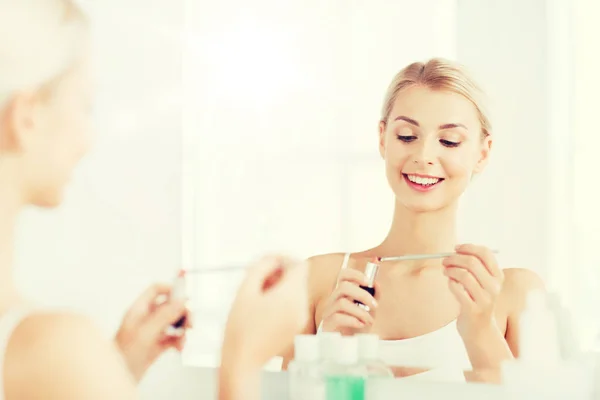 Kvinna med läppstift tillämpa make up på badrum — Stockfoto