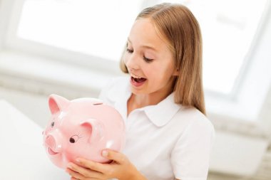 happy girl with piggy bank at home clipart