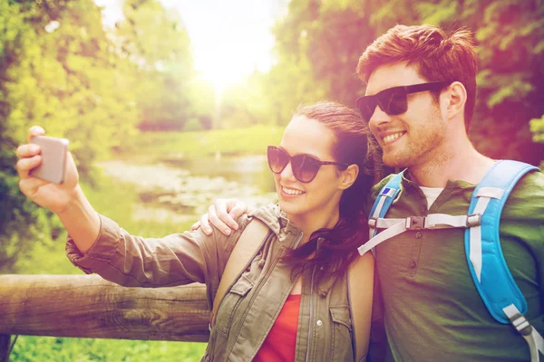 Echtpaar met rugzakken selfie te nemen door smartphone — Stockfoto