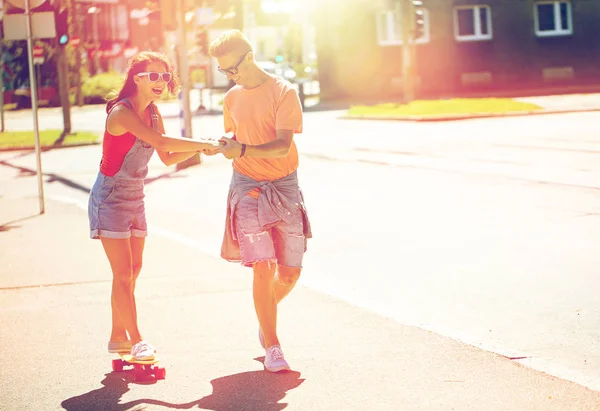 Pareja adolescente montando monopatines en la calle de la ciudad — Foto de Stock