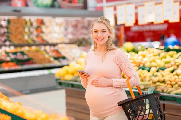 Schwangere mit Einkaufskorb und Smartphone — Stockfoto