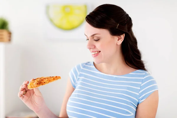 Happy woman eating pizza at home kitchen — Stock Photo, Image