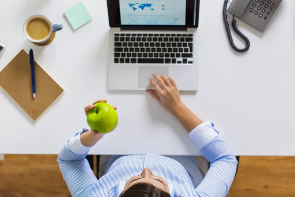 Empresária com maçã e laptop no escritório — Fotografia de Stock