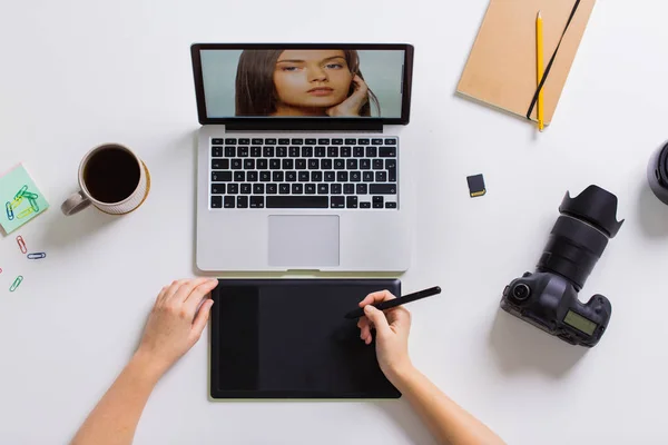Vrouw met camera werken op de laptop aan tafel — Stockfoto